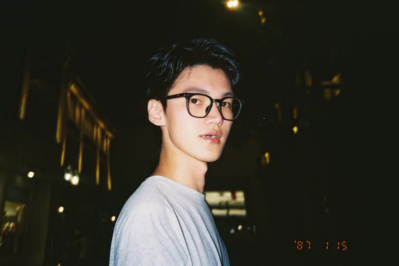 夜晚的灯光下，他侧过身回头看向镜头