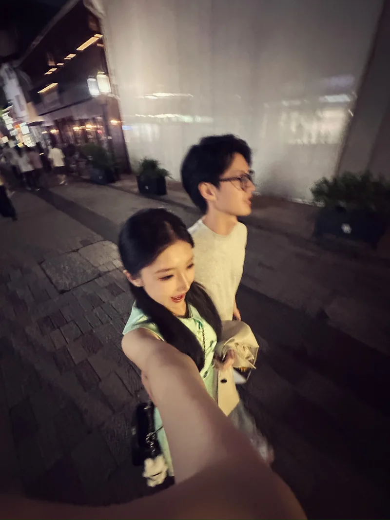 饭后两人在亮着灯的街道上并肩散步，她举起镜头拍下合照