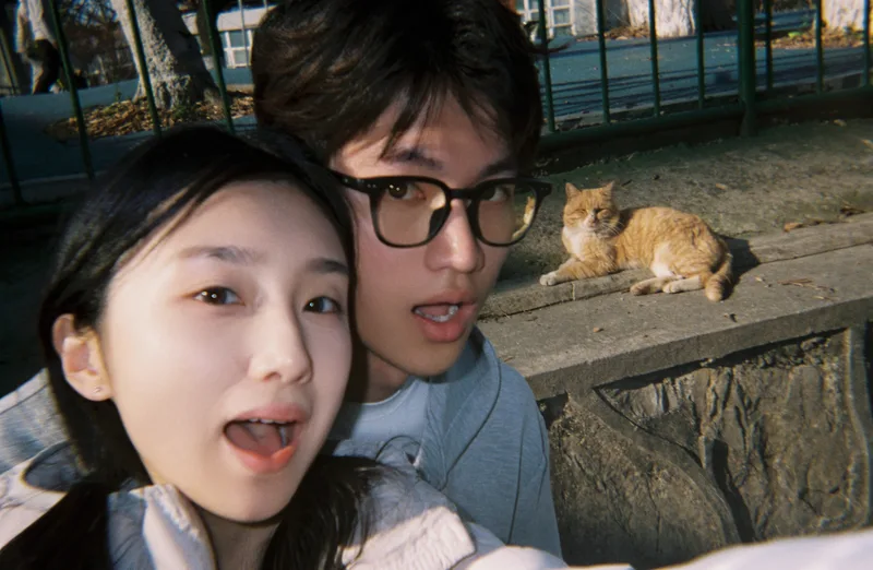 两人和石台上趴着的橘猫一起自拍